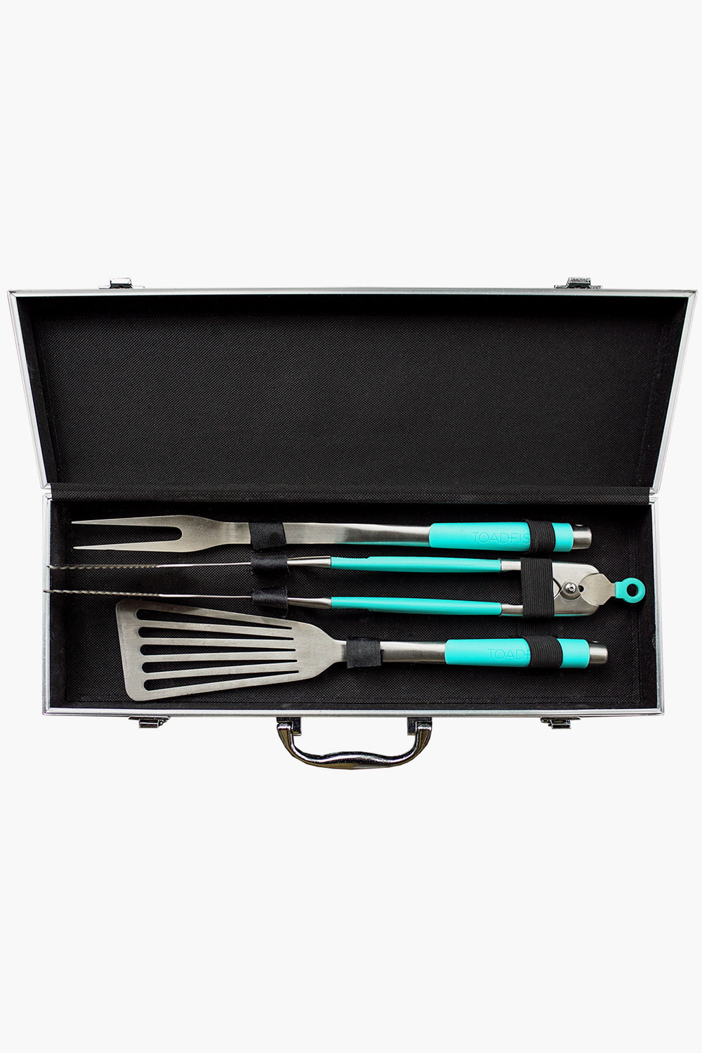The Toadfish metal case holds a stainless steel grill set with three tools—fork, spatula, and tongs—all featuring teal handles and secured inside with black straps.