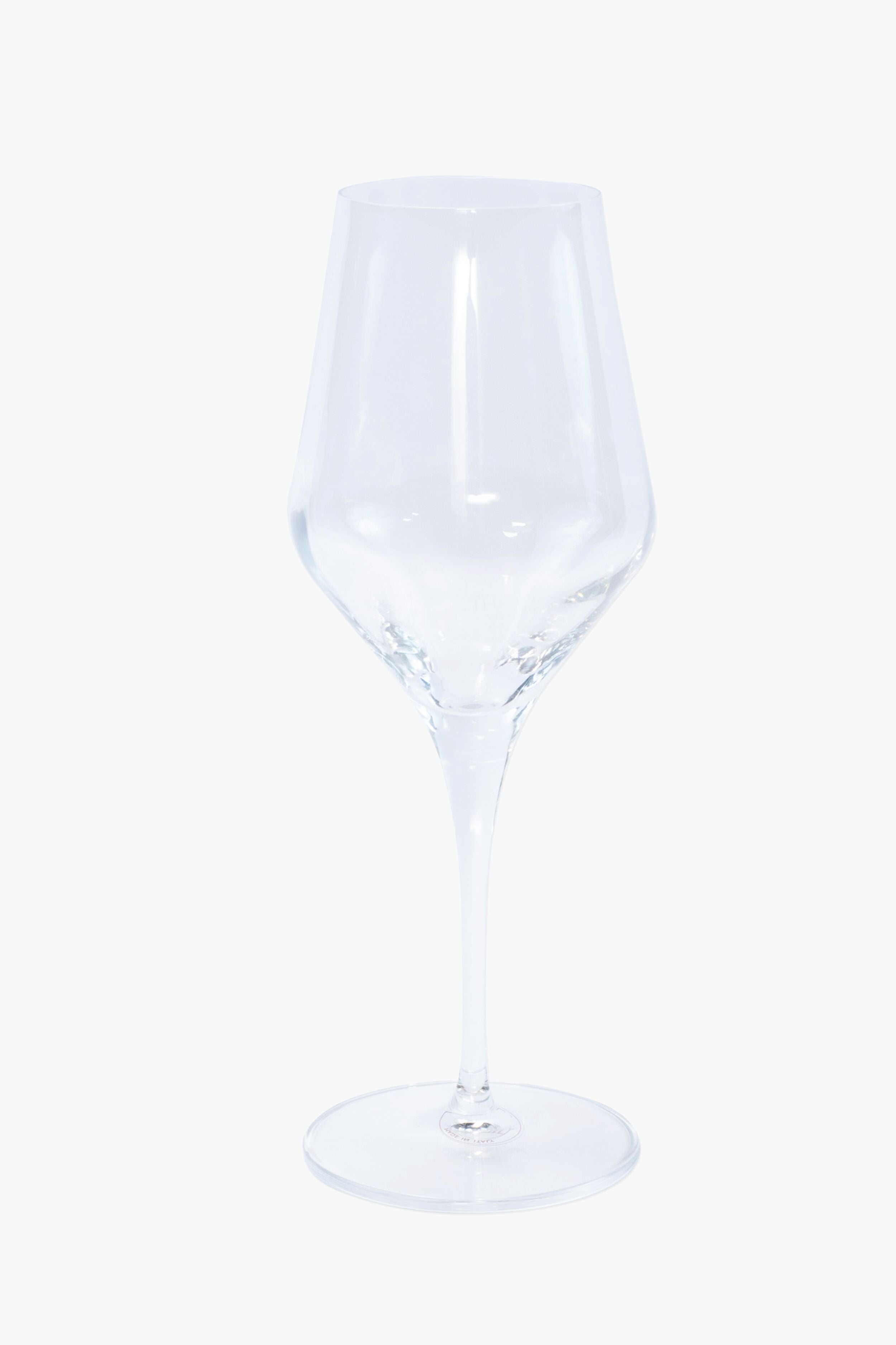 A clear, empty Vietri handmade wine glass with a thin stem and wide base sits elegantly—perfect for pairing with Italian ceramic dinnerware.
