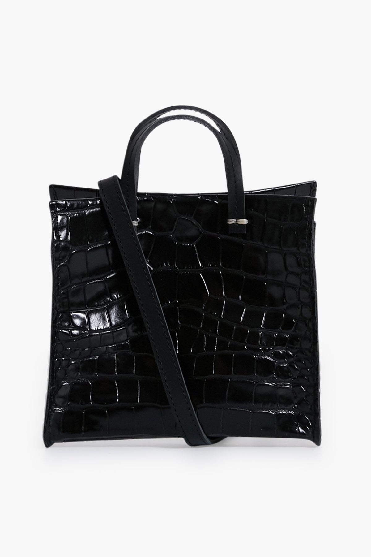 A Clare V black leather crossbody bag featuring a croc-embossed texture, two short handles, and a long shoulder strap draped across the front.