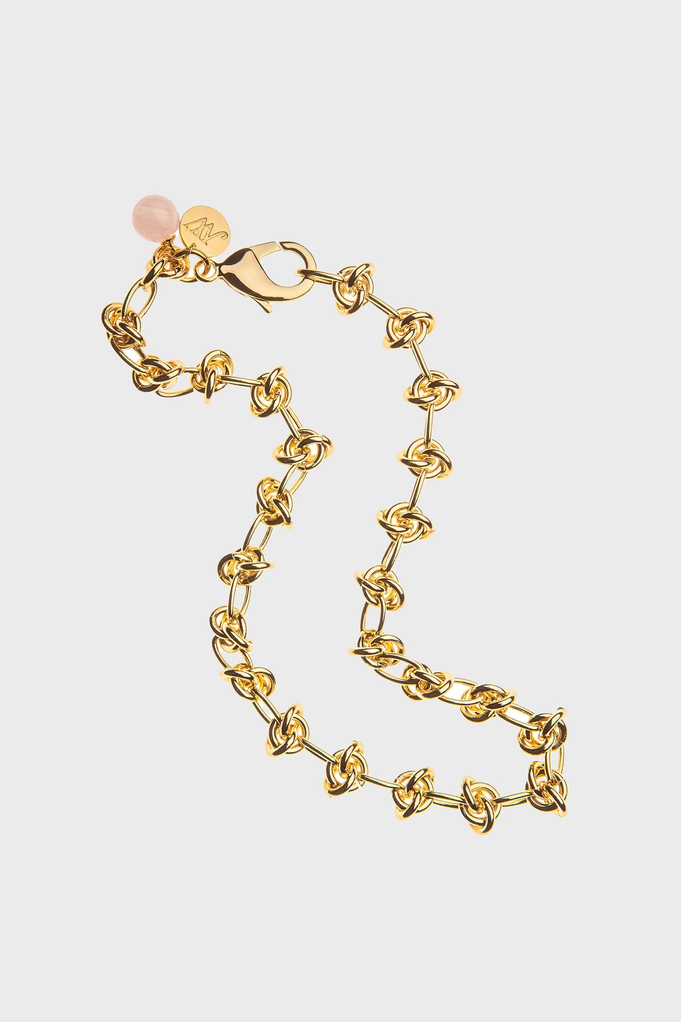 Jane Win 14k gold-plated chain bracelet with interlocking knot links, lobster clasp, small round pink charm, and gold tag.
