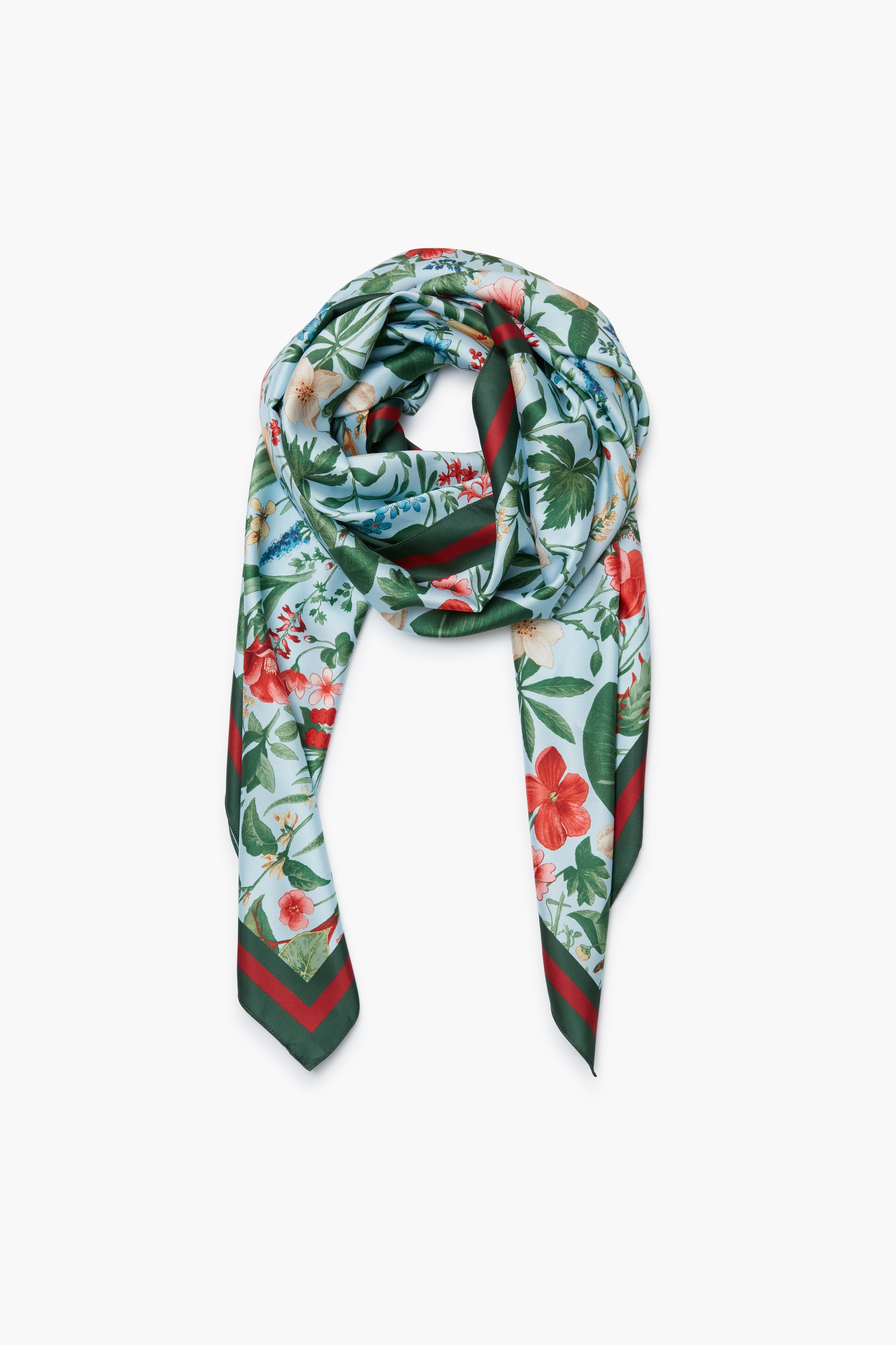 A Tuckernuck Accessories silk Blue Blooming Botanical Scarf, featuring a vibrant floral print in red, green, and blue hues, is styled in a loose knot—an elegant choice for a luxe accessory or those desiring a custom look.