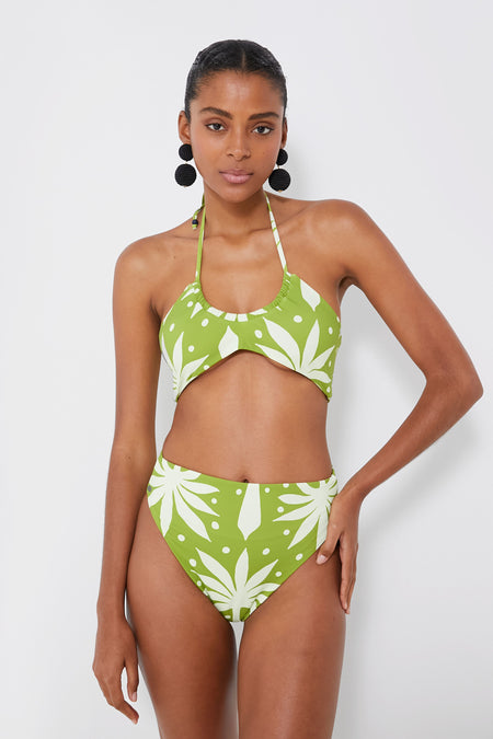 A woman wears the Cala de la Cruz Amalfi Lime Elia Top, a green and white high-waisted bikini with geometric botanical prints and a halter neck—ideal for resortwear.