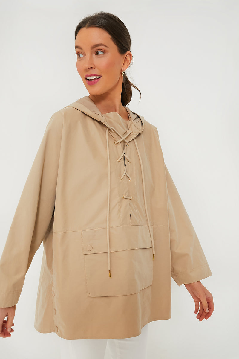 A woman wears a Pomander Place Beige Sterling Pullover, a loose-fitting, lightweight hoodie with a lace-up front and front pocket.