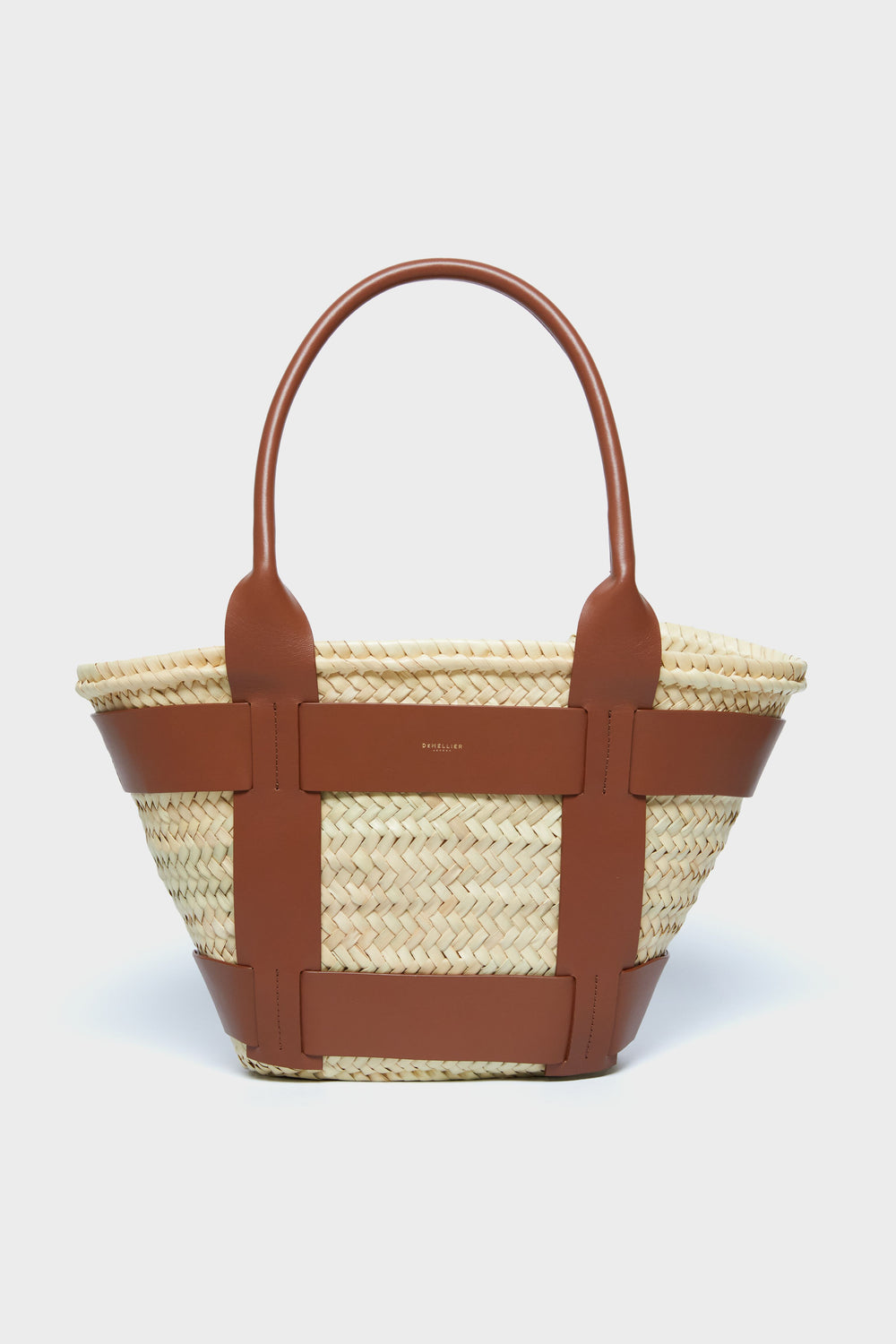 The Demellier woven raffia bag features brown leather handles and accents, blending handcrafted elegance with the charm of a luxury tote.