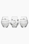 Three clear, round Juliska glasses with decorative raised patterns—two with spiral designs and one with circular accents—are crafted from mouth-blown Czech glass, making them a unique table centerpiece.