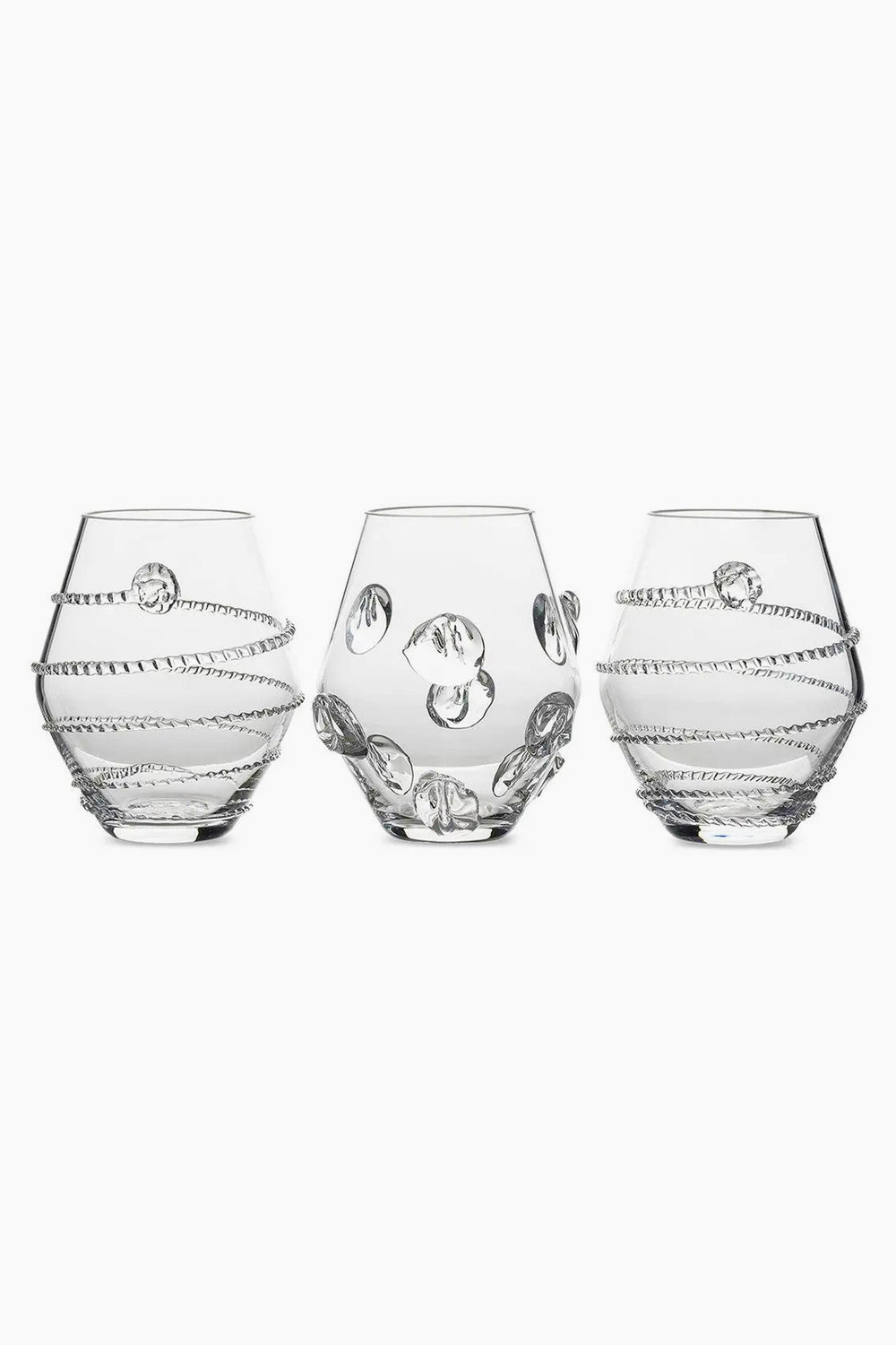 Three clear, round Juliska glasses with decorative raised patterns—two with spiral designs and one with circular accents—are crafted from mouth-blown Czech glass, making them a unique table centerpiece.