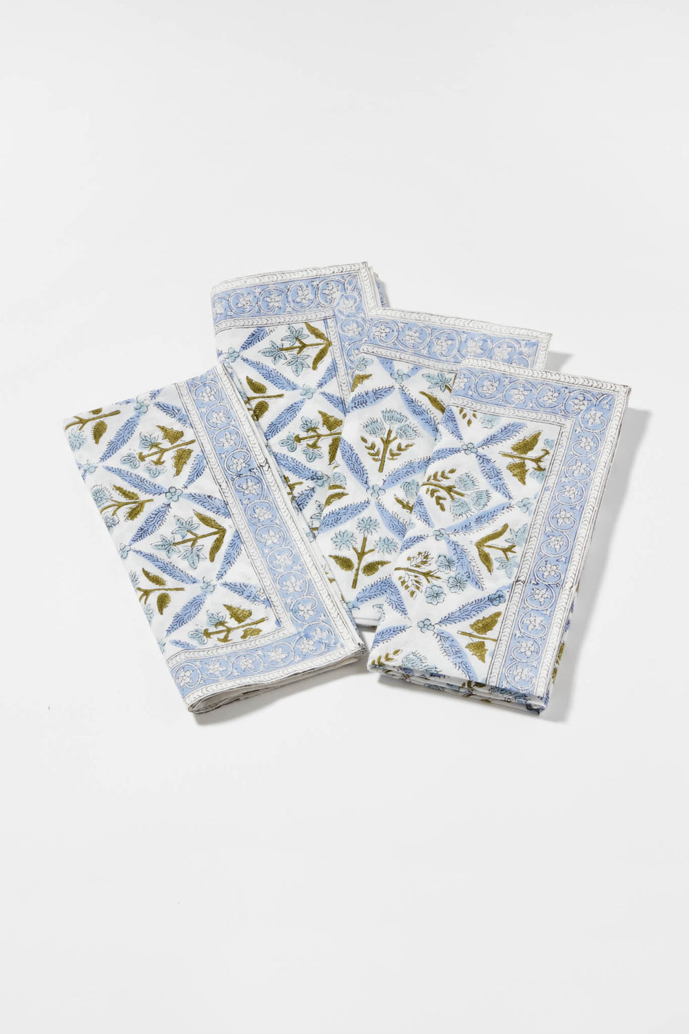 Three folded cotton napkins by Locust Walk feature a blue floral and geometric pattern, inspired by Hydrangea Blue Garden Trellis Napkins.
