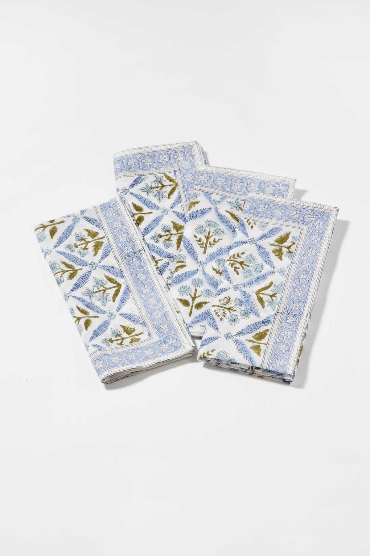 Three folded cotton napkins by Locust Walk feature a blue floral and geometric pattern, inspired by Hydrangea Blue Garden Trellis Napkins.