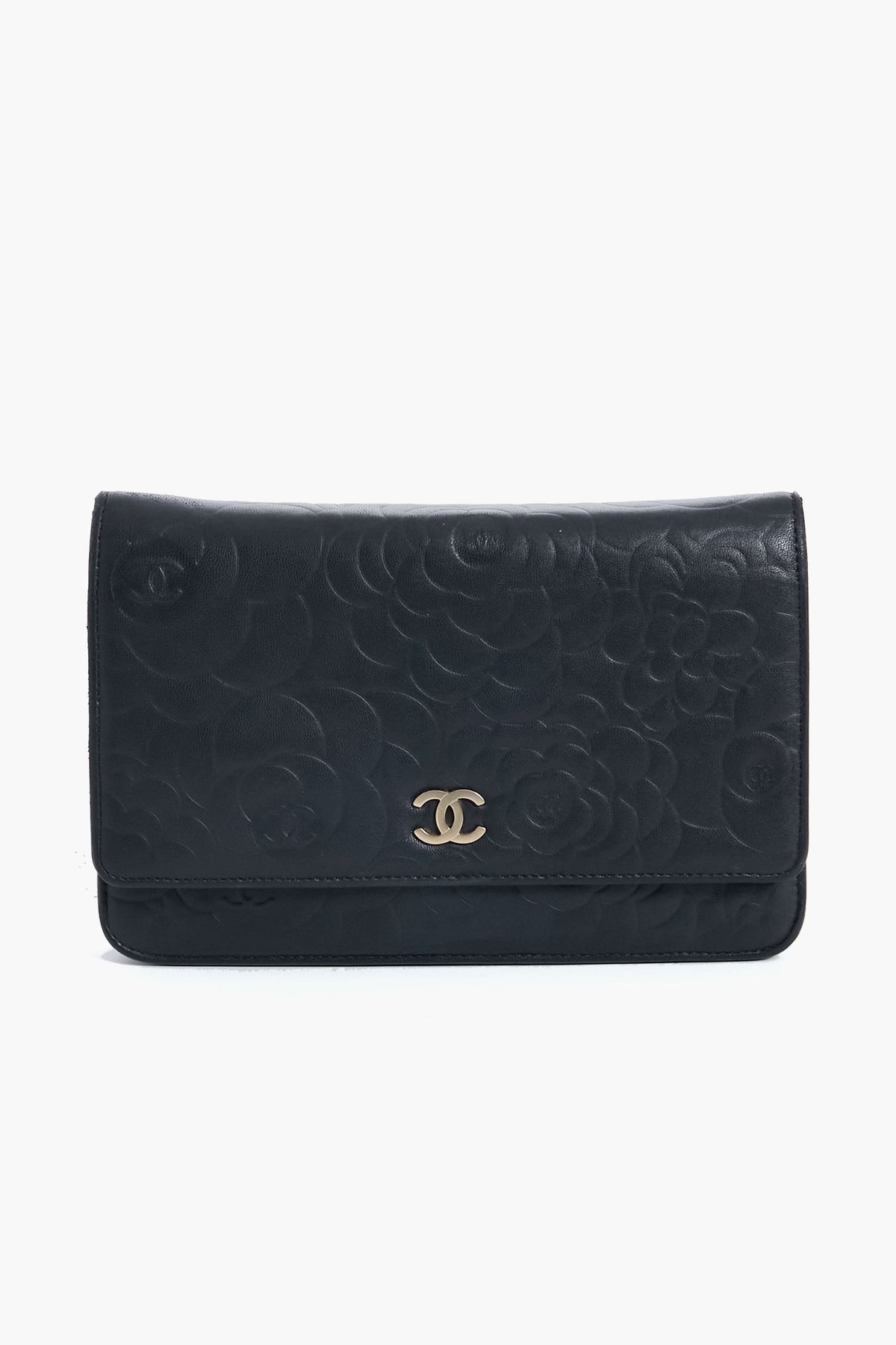 A black leather clutch from Tuckernuck Archive Collection featuring an embossed floral pattern and a gold logo on the front flap.