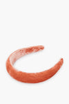 A wide, padded puffy headband by Loeffler Randall, covered in soft peach velvet.