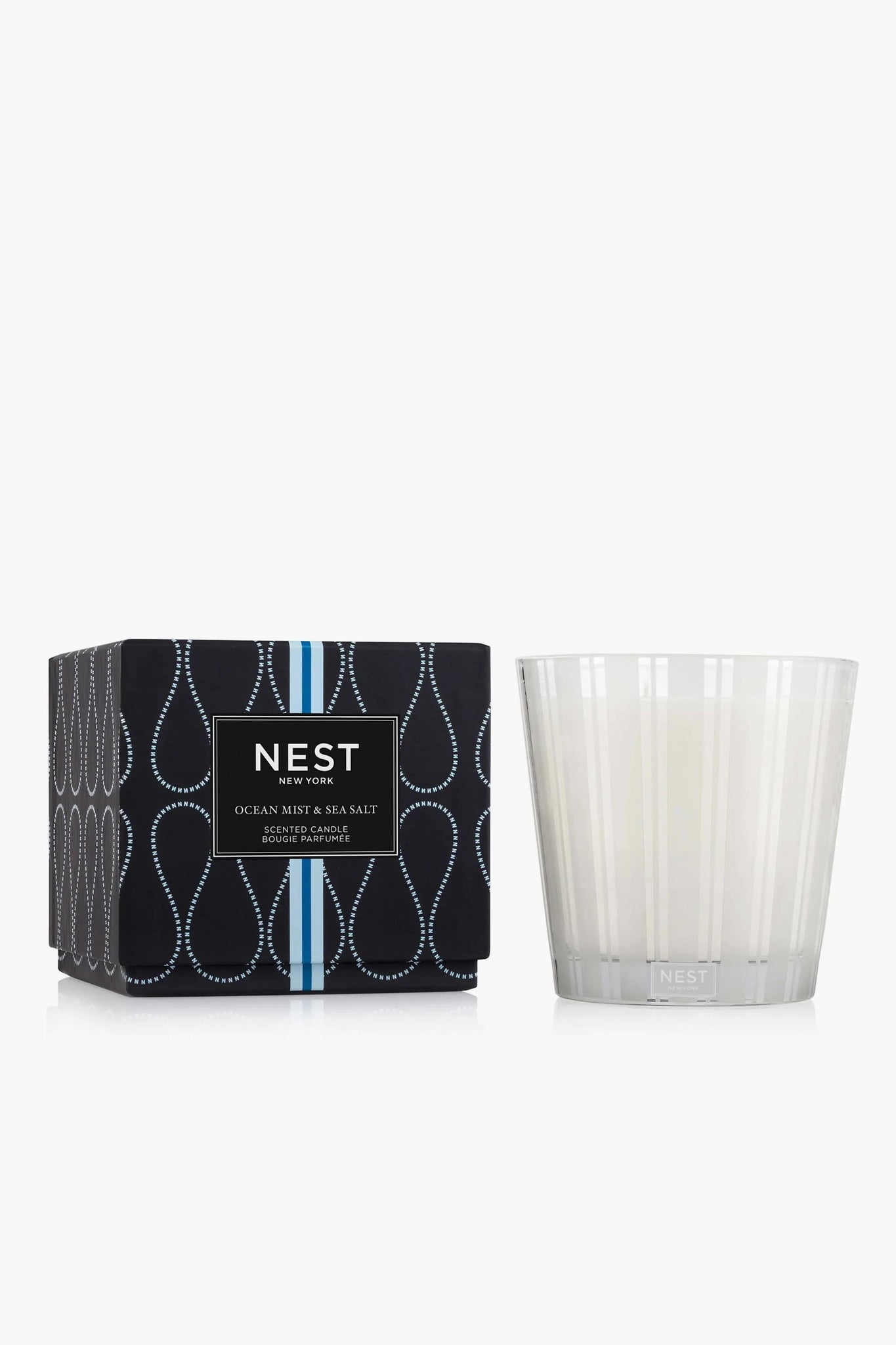 The NEST New York Ocean Mist & Sea Salt 3-wick candle, in a white glass holder beside its patterned black and blue box, offers a refreshing home fragrance experience.