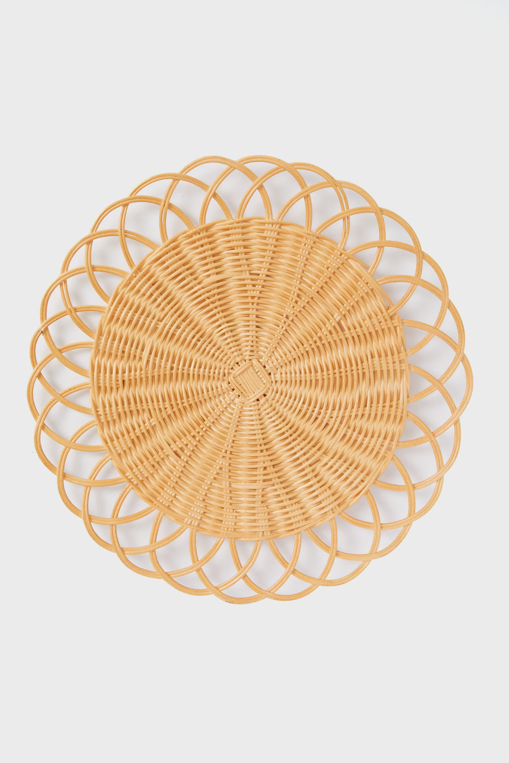 The Tuckernuck Home round wicker placemat, featuring an intricate looped edge design, brings elegant style to your tabletop.