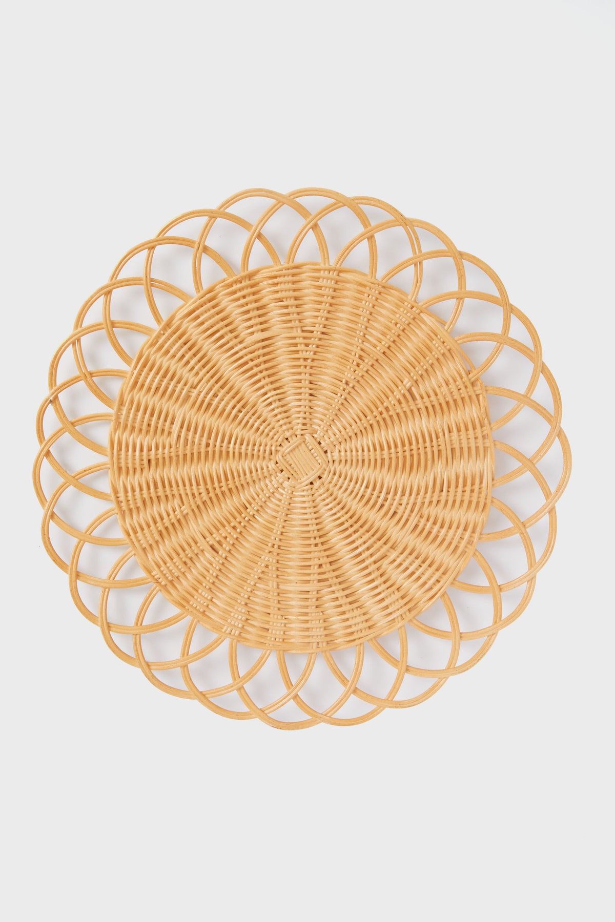 The Tuckernuck Home round wicker placemat, featuring an intricate looped edge design, brings elegant style to your tabletop.
