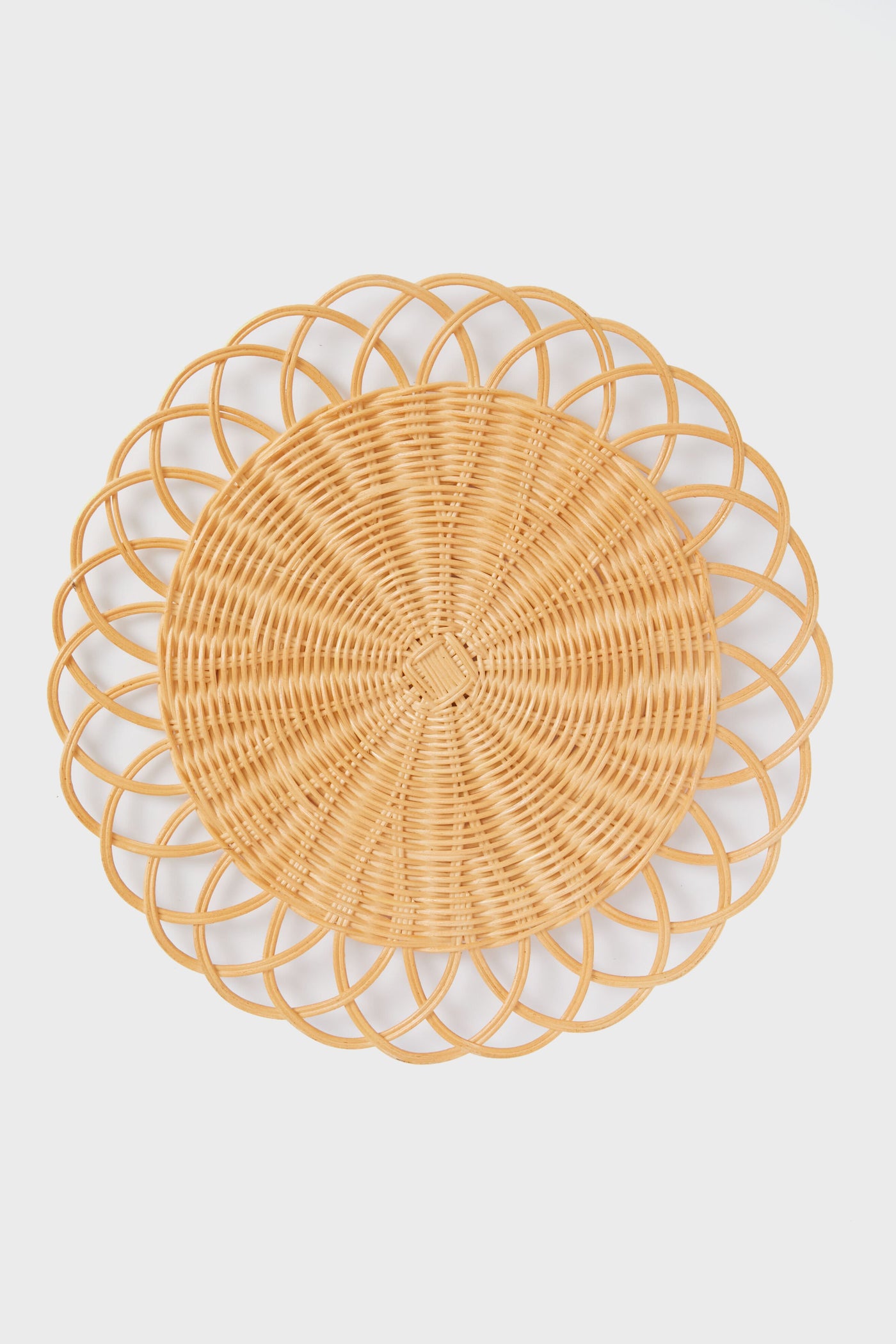 The Tuckernuck Home round wicker placemat, featuring an intricate looped edge design, brings elegant style to your tabletop.