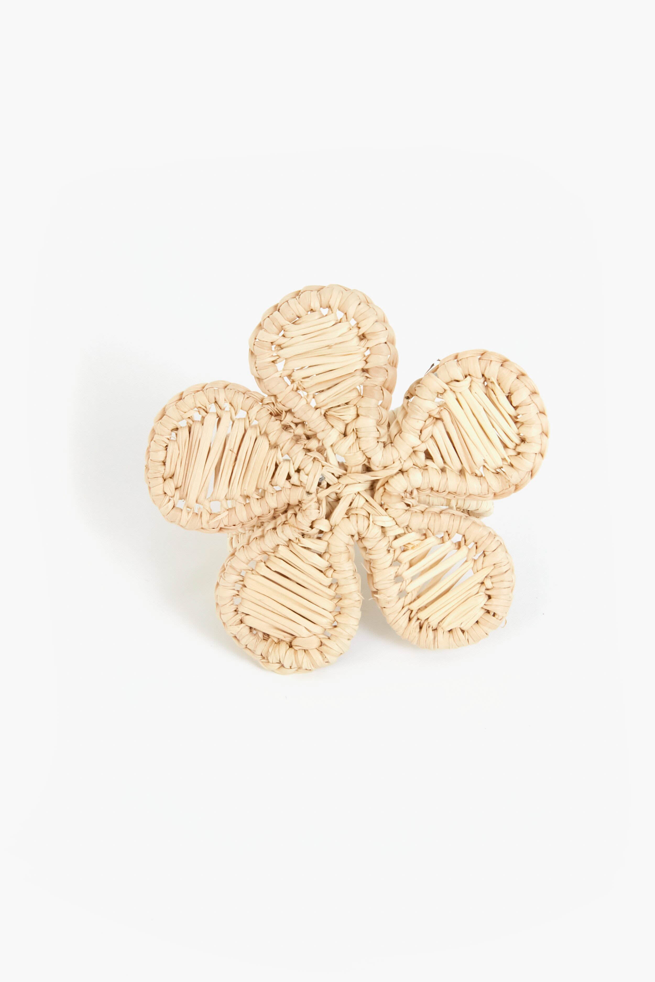 A woven straw napkin ring by Coro Cora, shaped as a five-petal flower and handmade from Iraca palm, offers unique Colombian artisan homeware style.