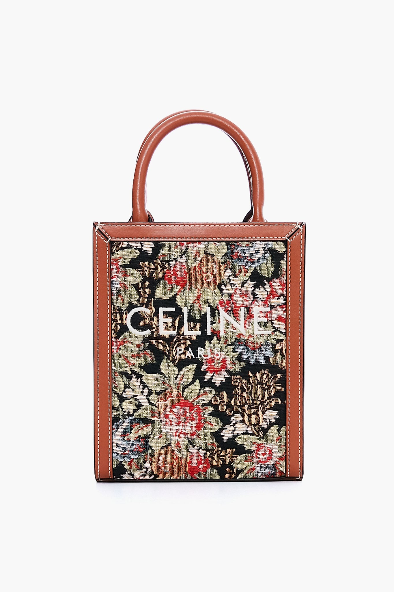 A rectangular Tuckernuck Archive Collection Small Vertical Cabas Tote with brown leather handles and trim, featuring a floral tapestry pattern on printed canvas and white logo text—perfect for luxury handbag lovers.