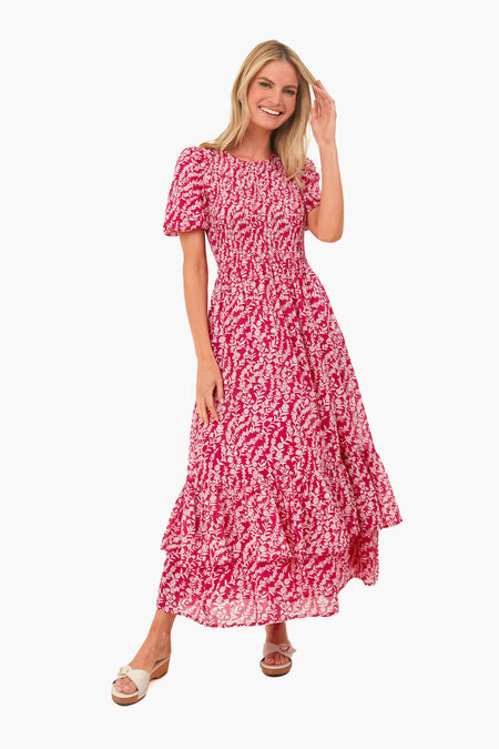 A woman stands smiling in a Banjanan pink and white floral print organic cotton maxi dress with short puff sleeves, handmade embroidery, and white sandals.