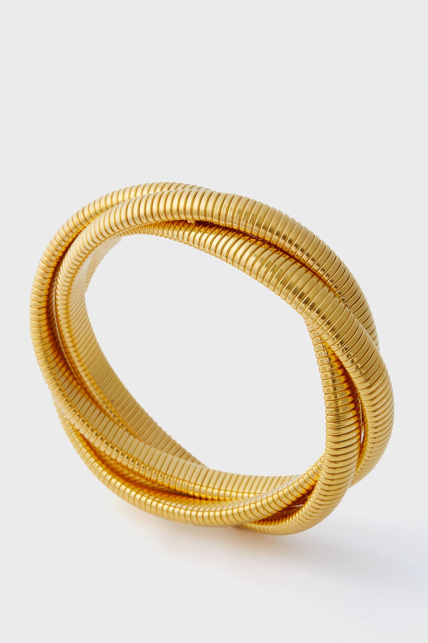A gold cobra bracelet by Ben Amun, coiled in an overlapping circular shape, creates a striking statement piece.