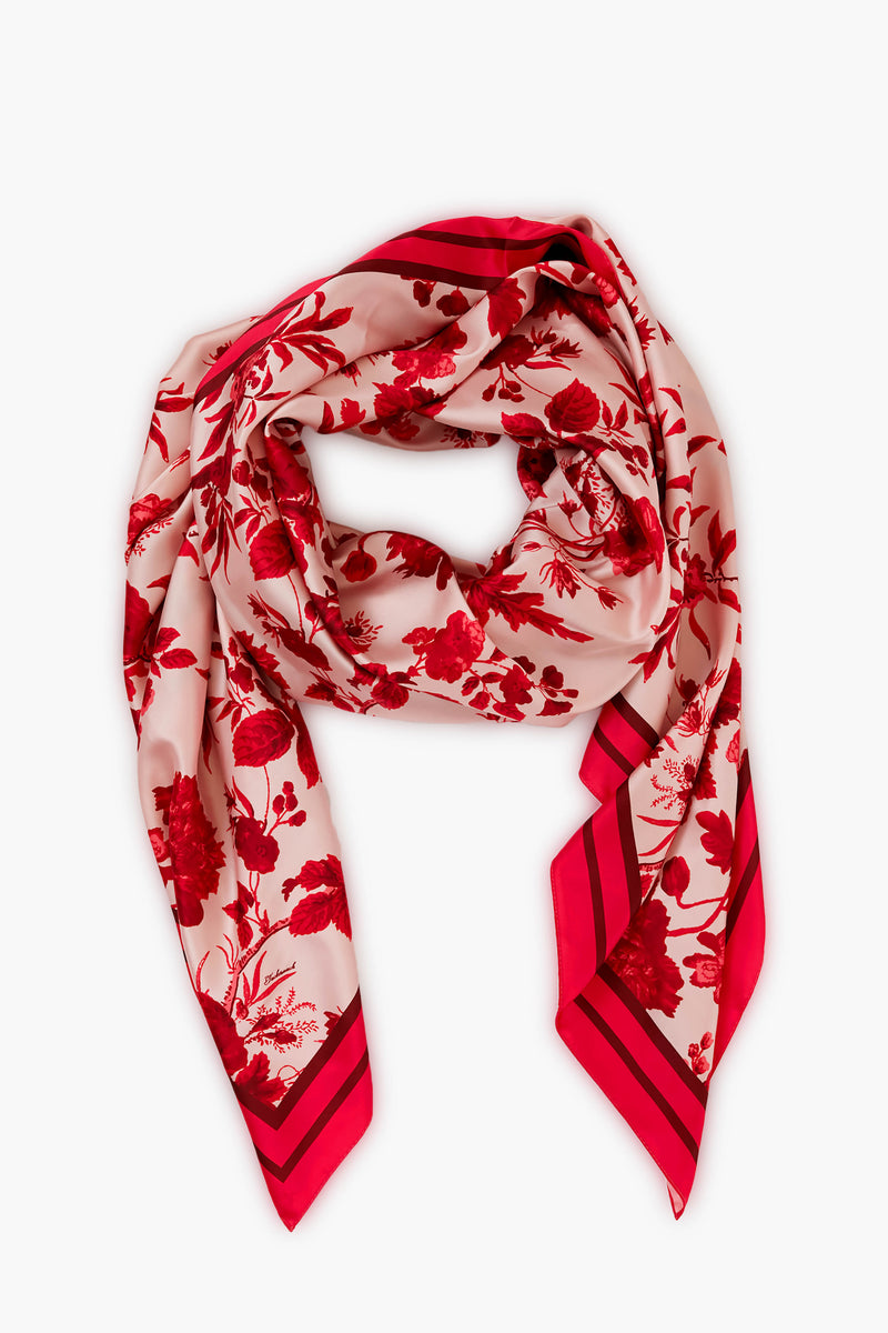 A Tuckernuck Accessories square silk scarf with a red floral print and striped border, shown flat with a gentle fold—a must-have style staple accessory.