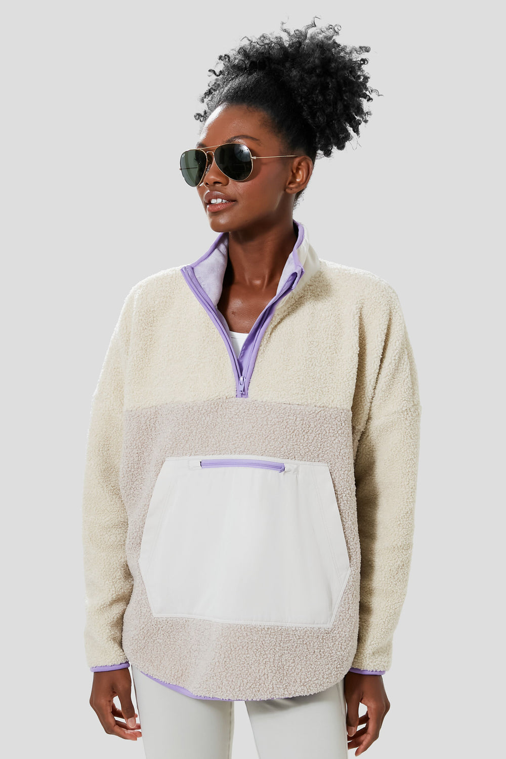 A person in sunglasses and a Tnuck Sport Gray and Lilac Fleece Cady quarter zip pullover with front pocket stands confidently, highlighting cozy style.