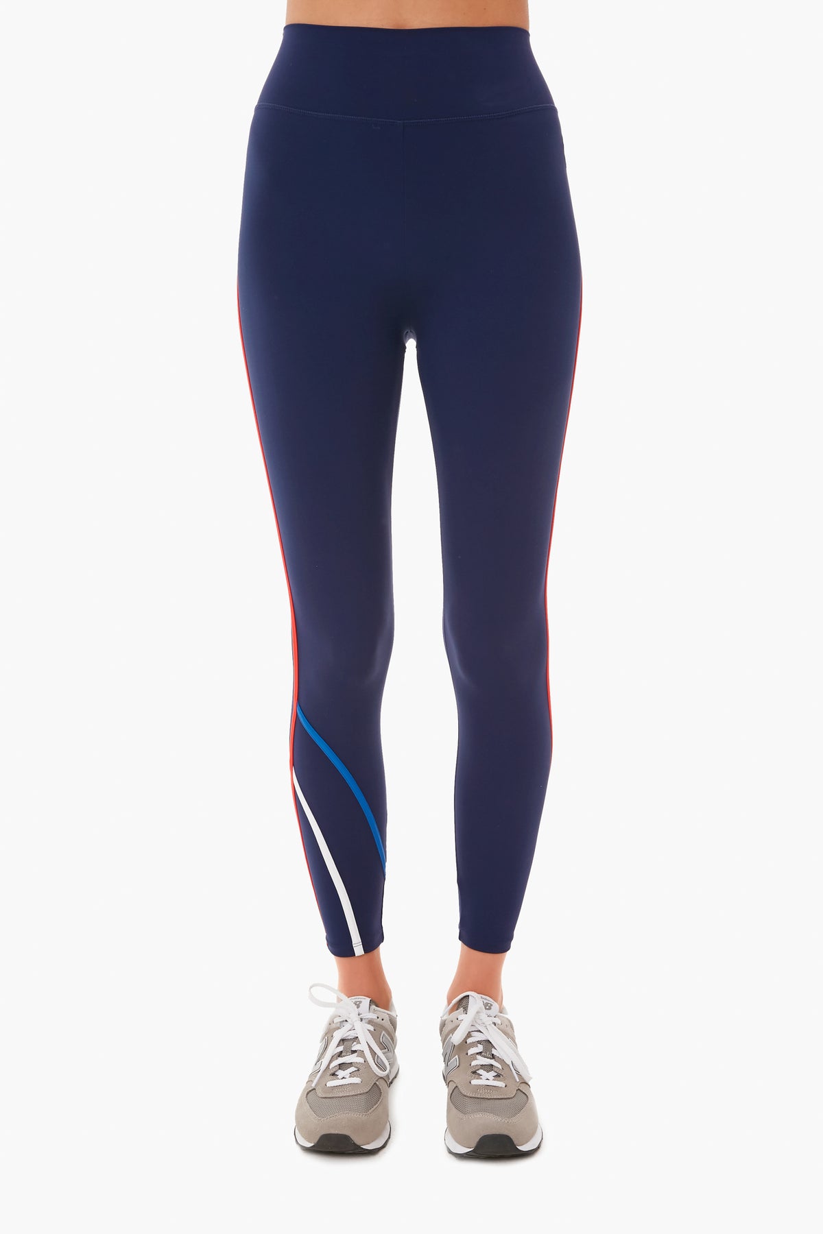 A person is wearing Addison Bay navy high-rise leggings with red, white, and blue side stripes, paired with gray sneakers.