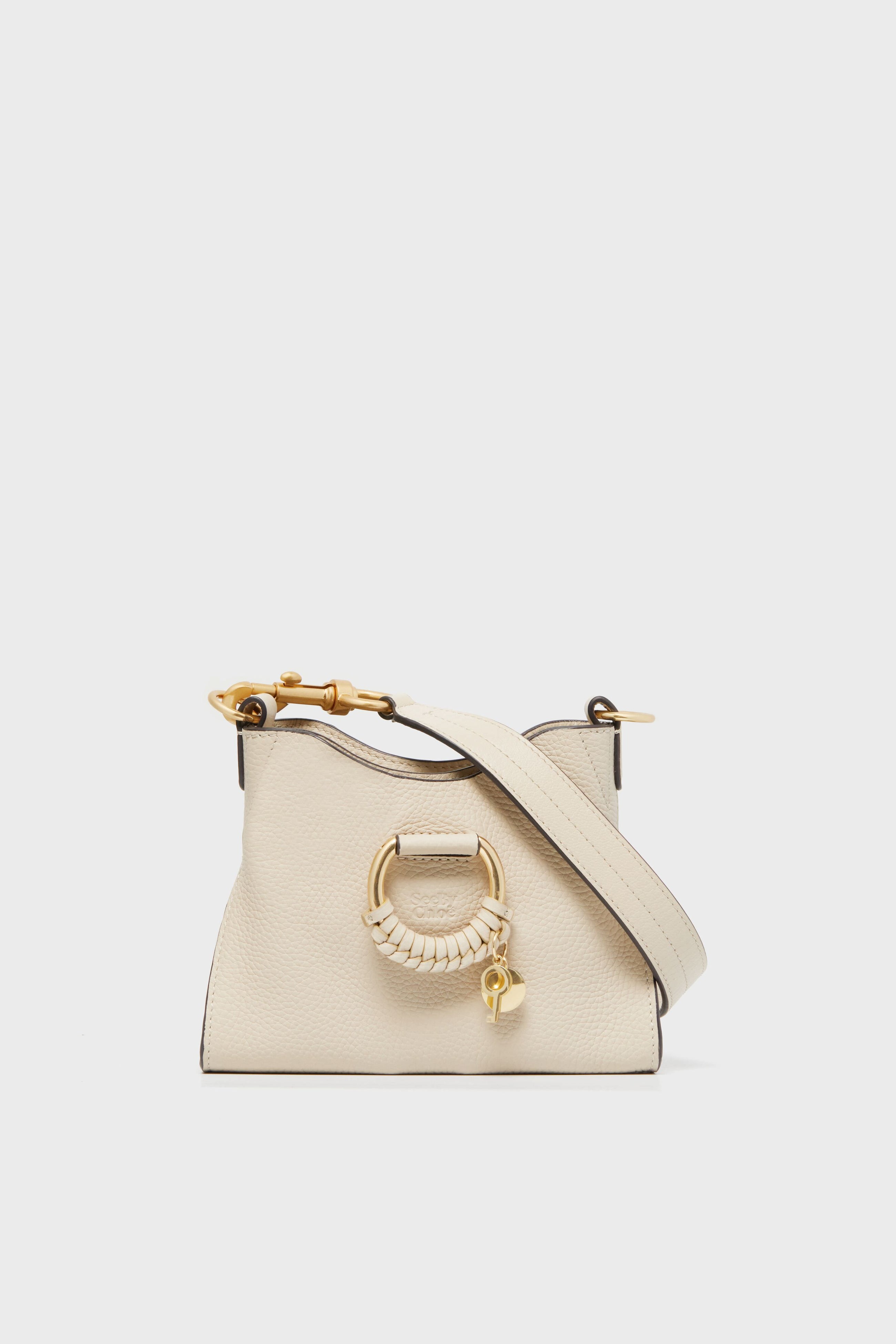 A compact off-white See by Chloe leather top handle purse with gold-toned ring and clasp details, a matching shoulder strap, and a minimalist design inspired by the iconic Joan Bag.