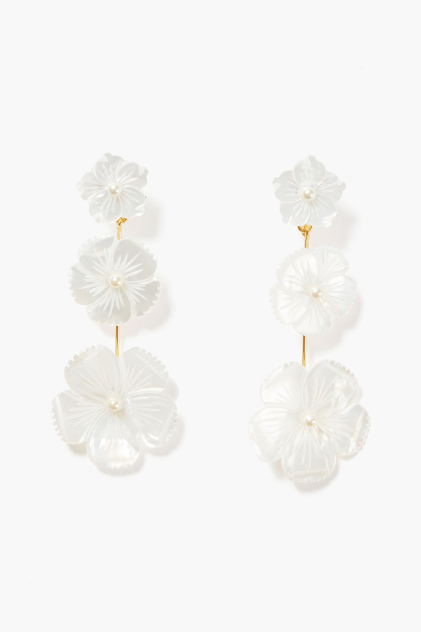 Jennifer Behr floral drop earrings feature three white carved flowers with pearl centers, linked by gold-toned metal and handmade in New York.