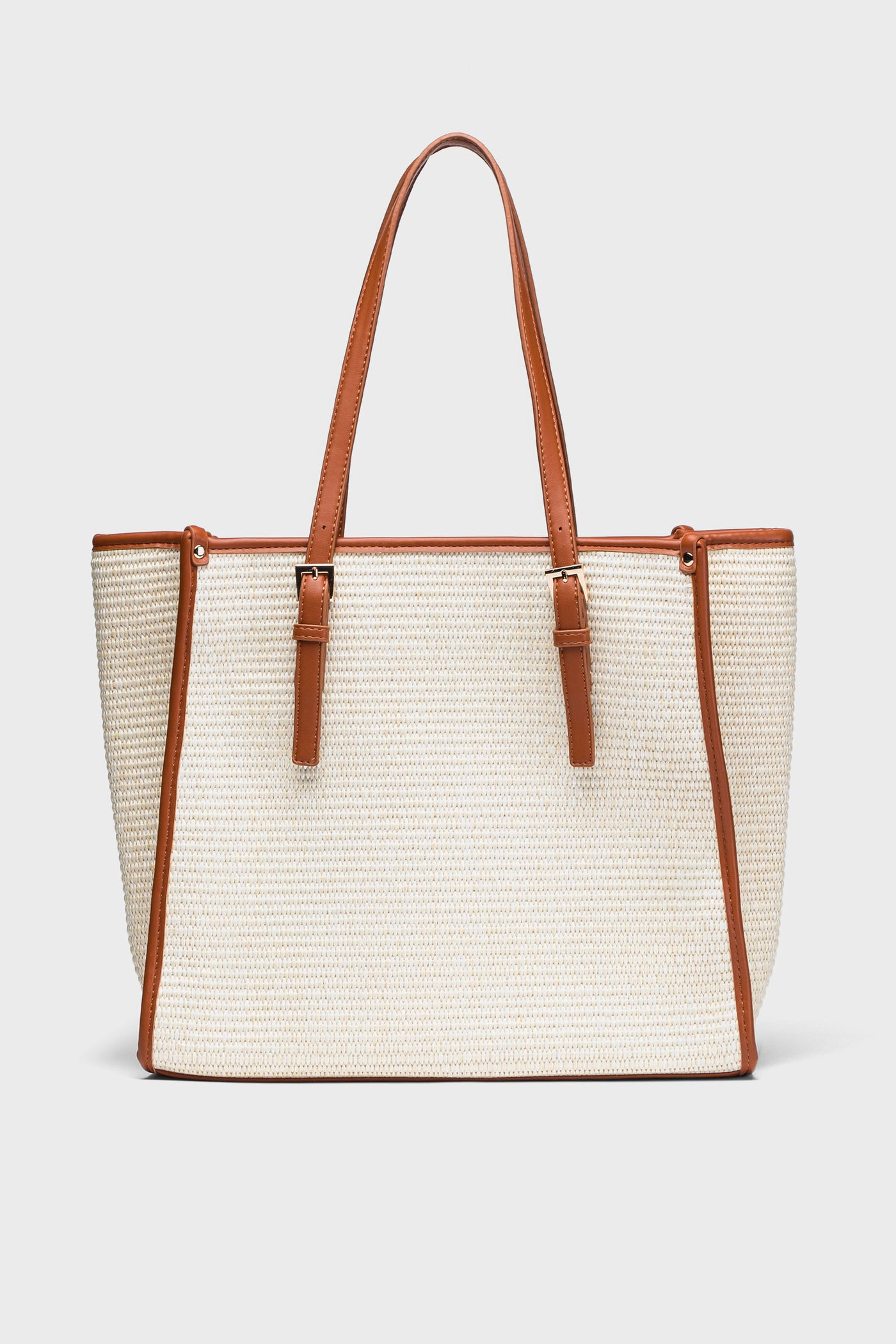 The Moda Luxe beige straw tote bag features brown vegan leather trim and handles, making it a chic choice for the beach.