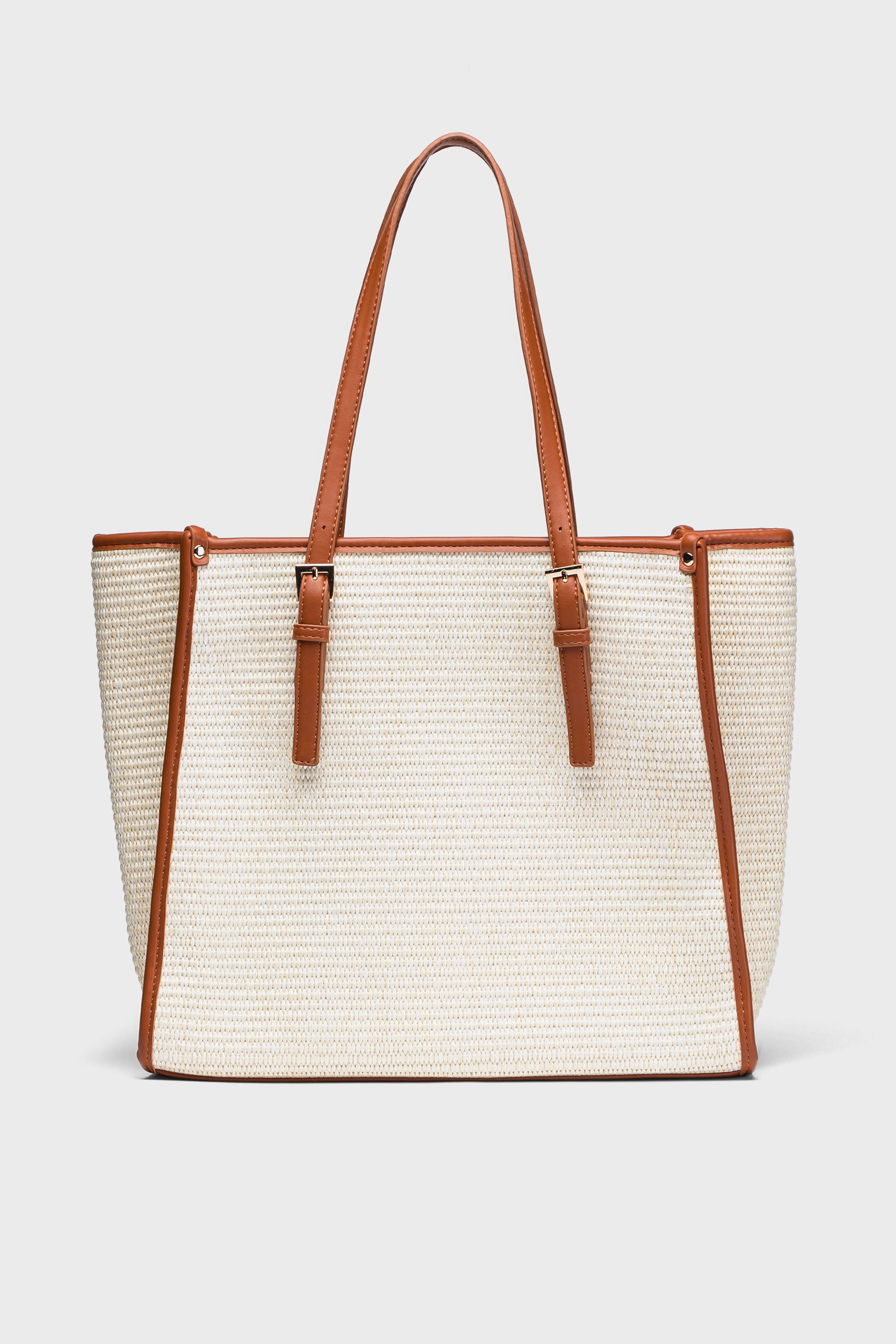The Moda Luxe beige straw tote bag features brown vegan leather trim and handles, making it a chic choice for the beach.