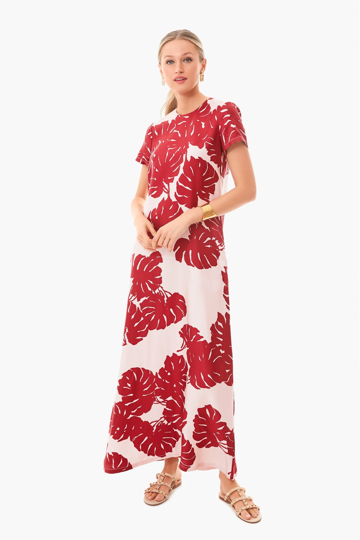 A woman wears a La DoubleJ red and white silk twill midi swing dress with a bold leaf print, gold bracelet, and tan sandals. Made in Italy.