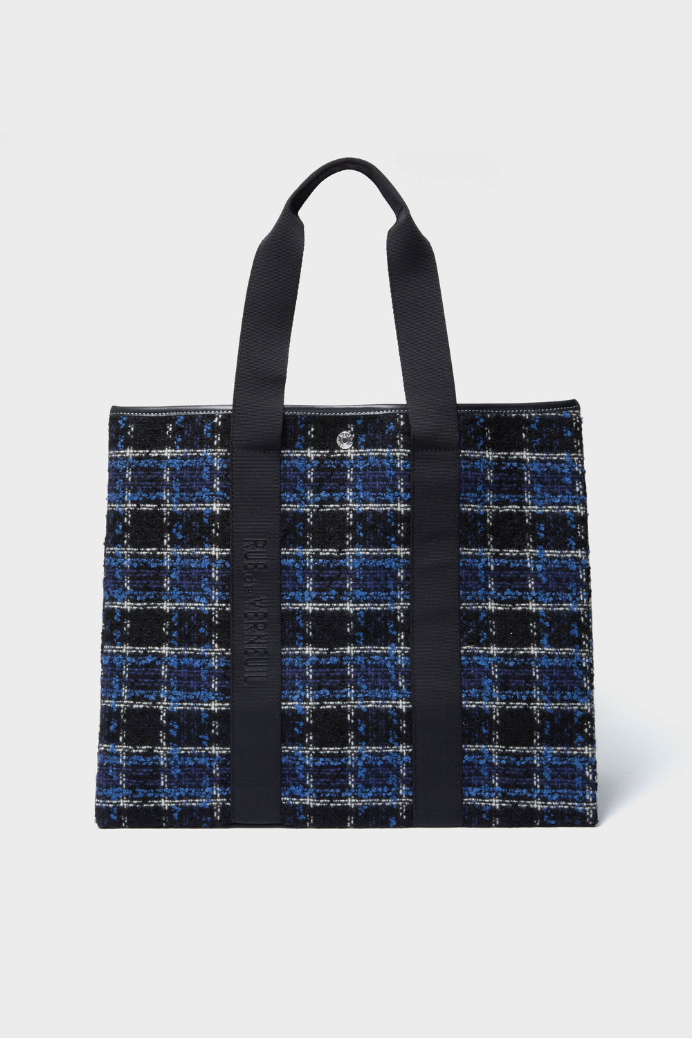 The Rue de Verneuil rectangular tweed tote bag features black handles and a blue, black, and white plaid pattern for a stylish, luxury luggage look.