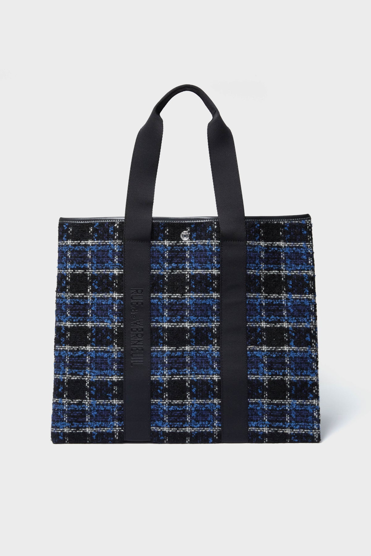 The Rue de Verneuil rectangular tweed tote bag features black handles and a blue, black, and white plaid pattern for a stylish, luxury luggage look.