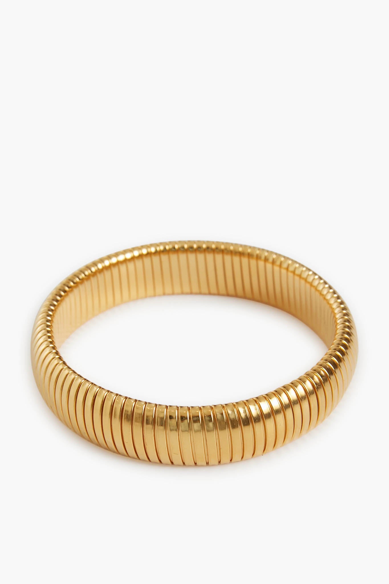 A gold-plated brass bangle by Ben Amun featuring a ribbed circular design and a smooth, reflective finish—an elegant statement bracelet.