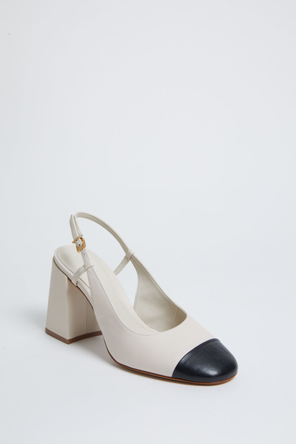 Beige slingback block heel by Schutz, featuring a chic black cap toe and stylish strap, embodying the brand's signature elegance.