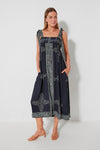 A woman wears an Alix of Bohemia navy blue hand block-printed Tencel maxi dress with white patterns and tan sandals—a travel-friendly, stylish choice.