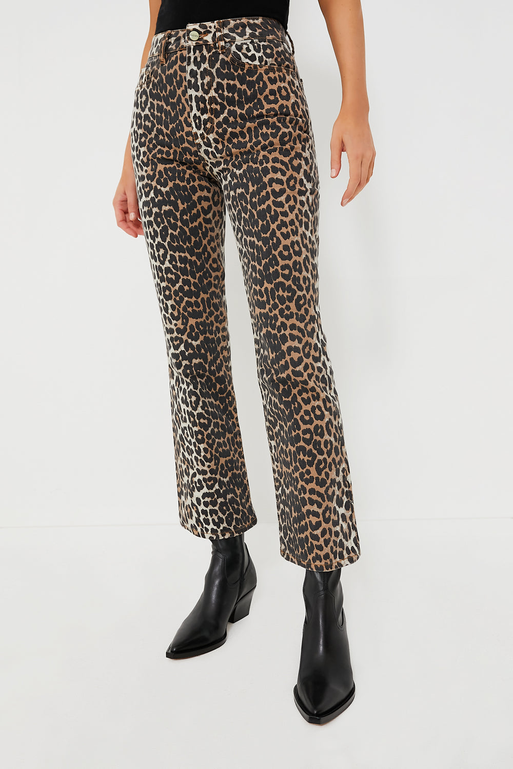 A person wears GANNI high waist cropped leopard print denim pants with black pointed-toe boots.