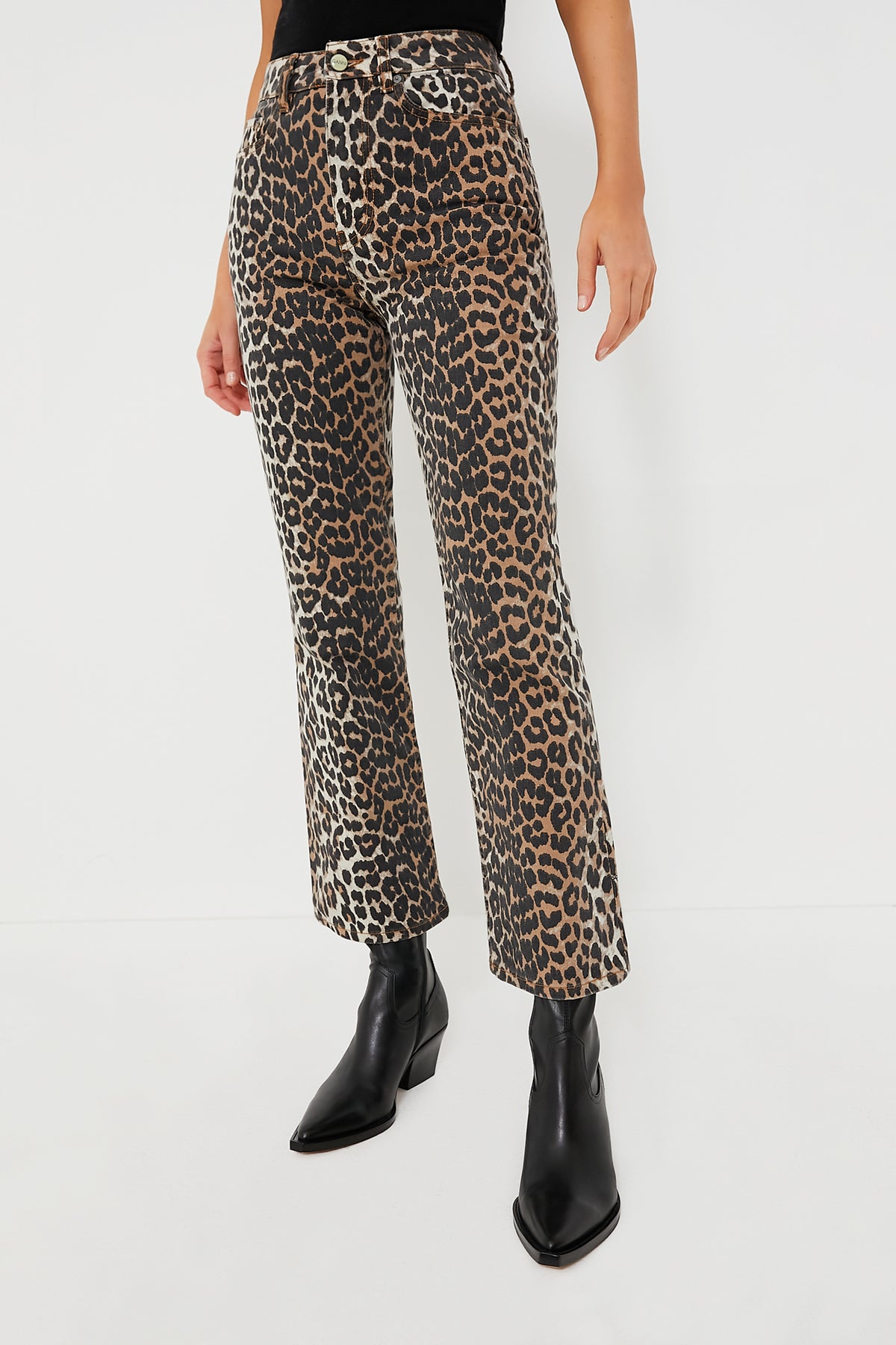 A person wears GANNI high waist cropped leopard print denim pants with black pointed-toe boots.