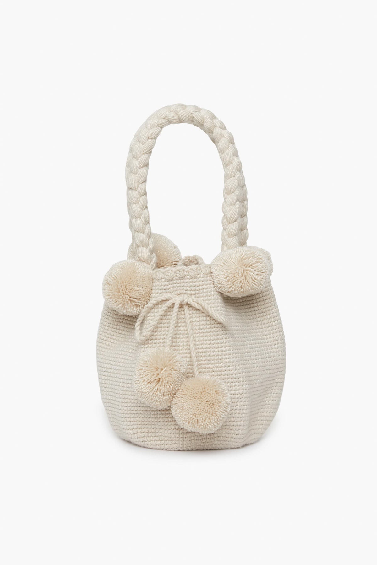 A cream-colored handwoven bag by Marina Orth Foundation from San Jacinto, Colombia, featuring braided handles and decorative pom-poms.