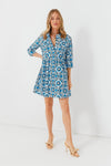 A woman wears a Tuckernuck blue medallion print shirt dress with three-quarter sleeves in soft cotton sateen, paired with beige heeled sandals.