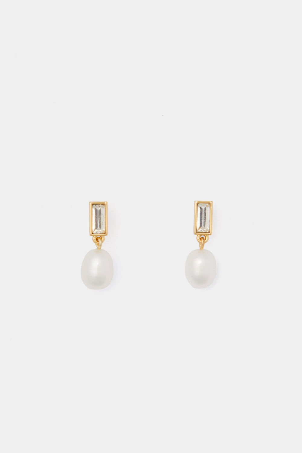 Tuckernuck Jewelry presents gold-plated crystal stud earrings featuring rectangular clear stones and dangling round white pearls for an elegant touch.