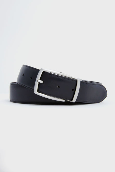 A black Peter Millar leather belt with pebble grain texture and a silver buckle is elegantly coiled.