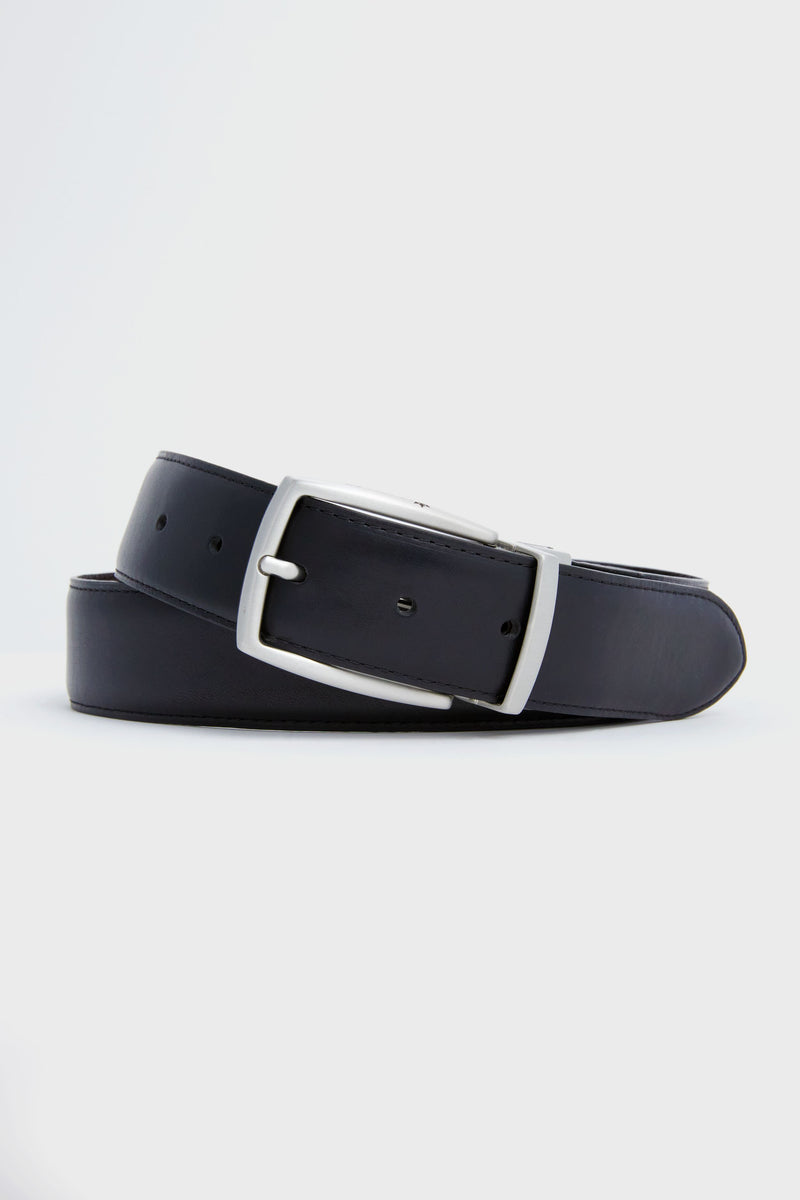 A black Peter Millar leather belt with pebble grain texture and a silver buckle is elegantly coiled.