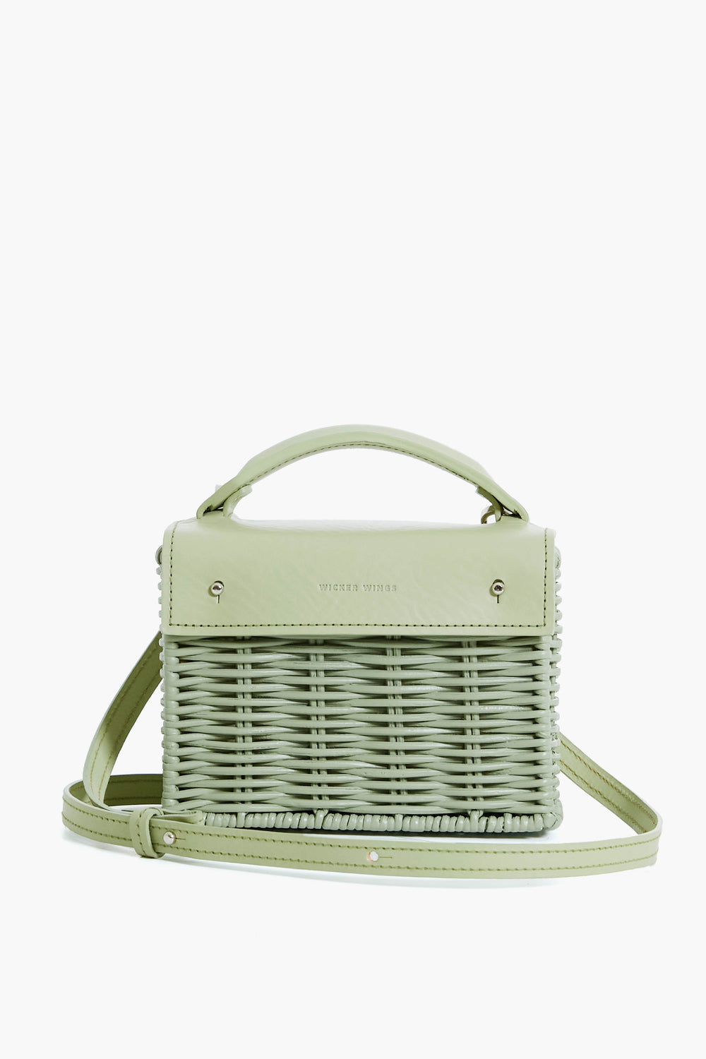 The Wicker Wings light green woven bag features a top handle, leather flap, adjustable shoulder strap, metal accents, and a structured rectangular shape. Made from sustainable materials, it offers modern style with eco-friendly appeal.