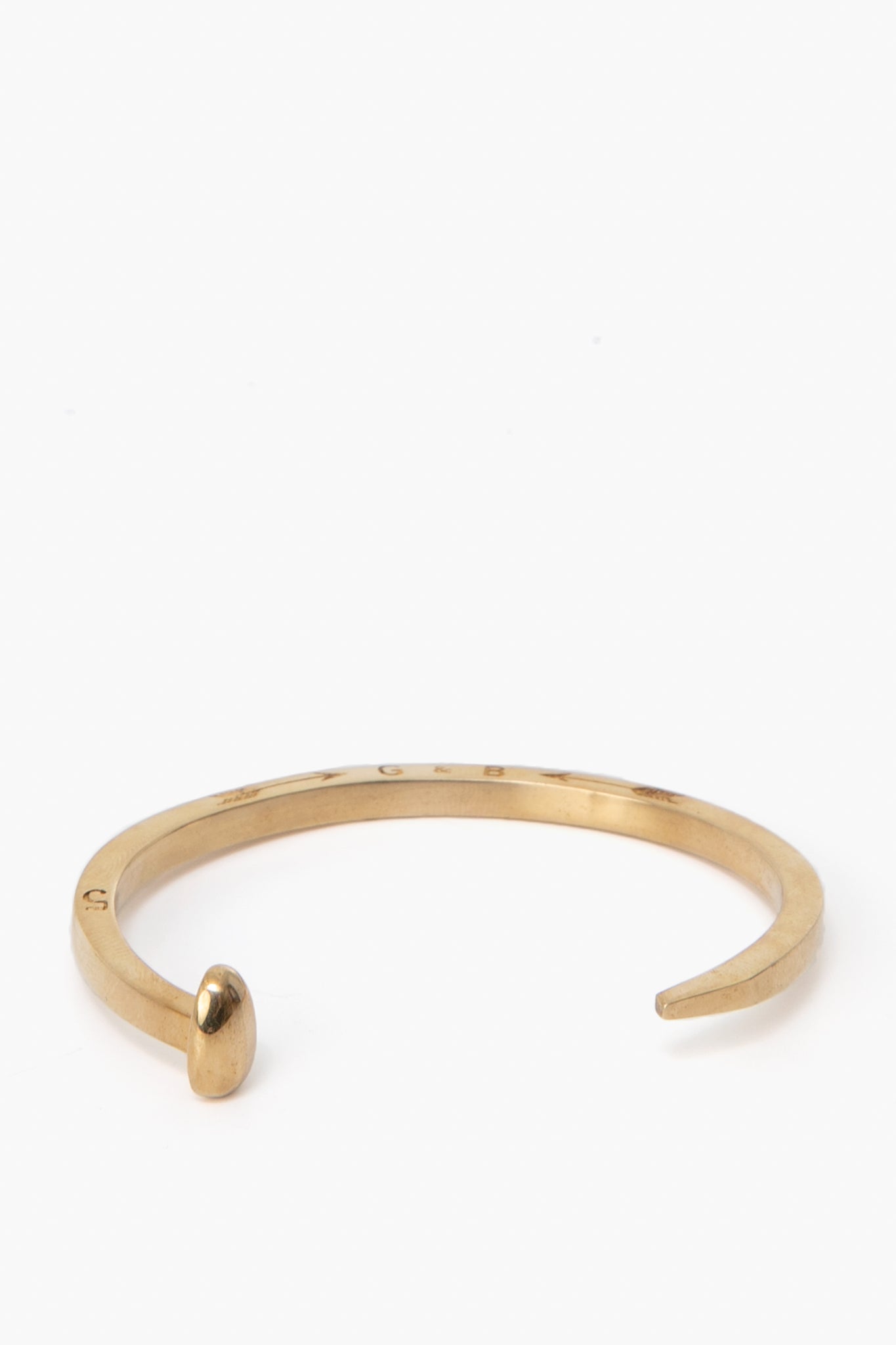 A gold Railroad Spike Bracelet by Giles and Brother, designed with a rounded tip on one end and a flat end on the other.