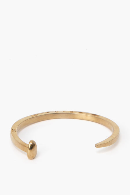 A gold Railroad Spike Bracelet by Giles and Brother, designed with a rounded tip on one end and a flat end on the other.
