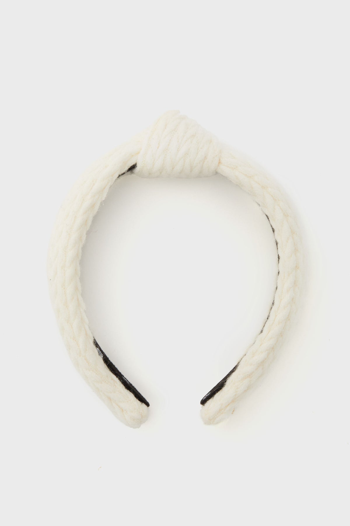 Lele Sadoughi white braided fabric headband featuring a top knot design, displayed in a minimalist setting.
