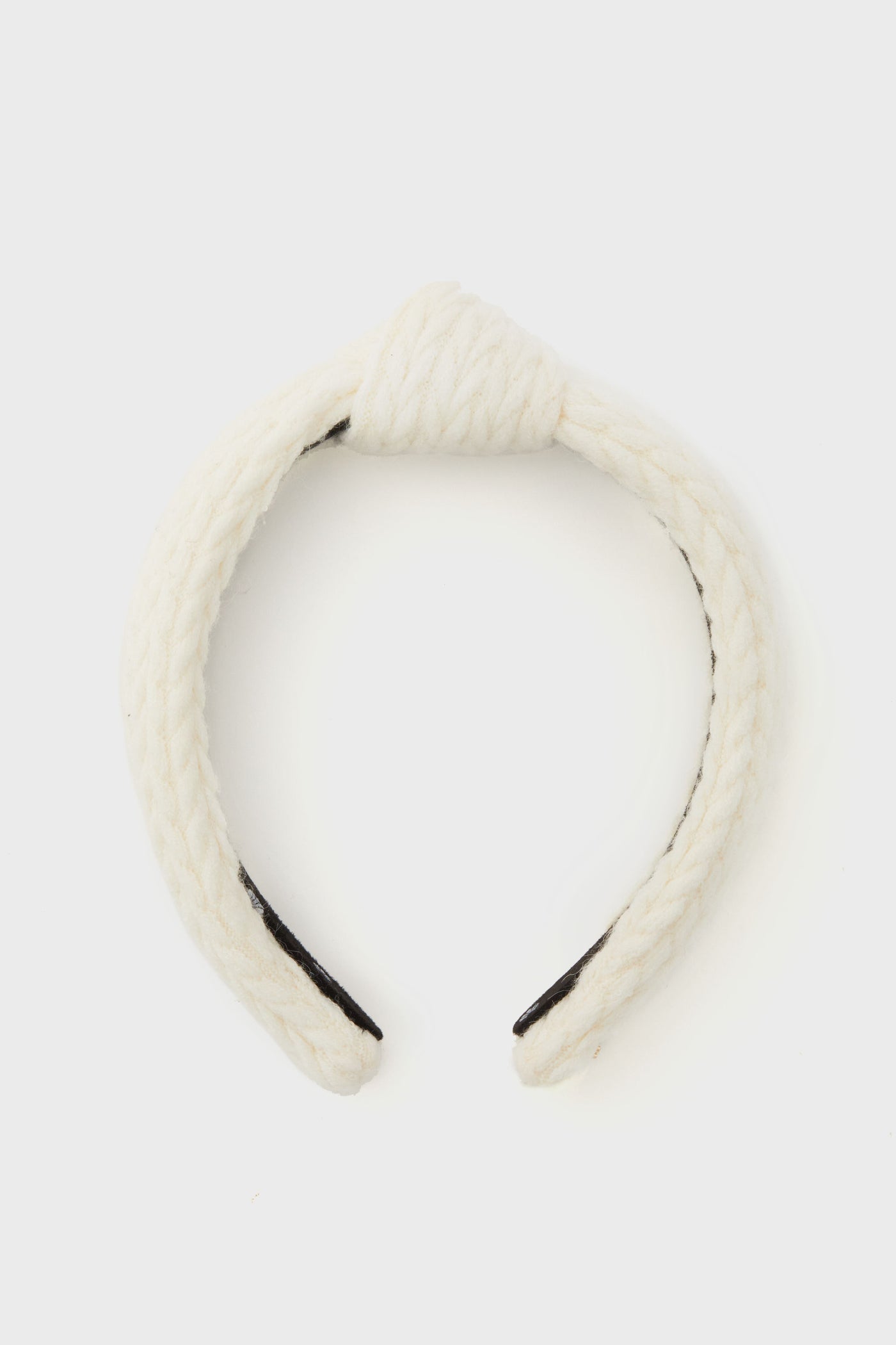 Lele Sadoughi white braided fabric headband featuring a top knot design, displayed in a minimalist setting.