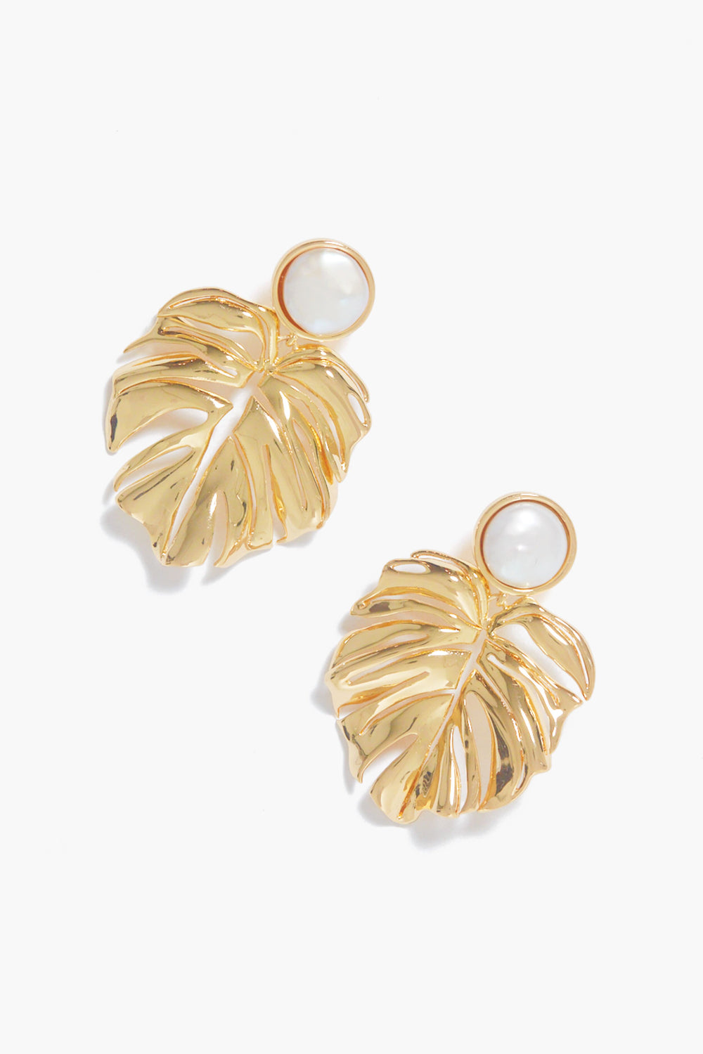 Mignonne Gavigan’s gold-plated Lux Palm Pearl Earrings feature elegant monstera leaf shapes with chic round white pearl accents at the top.