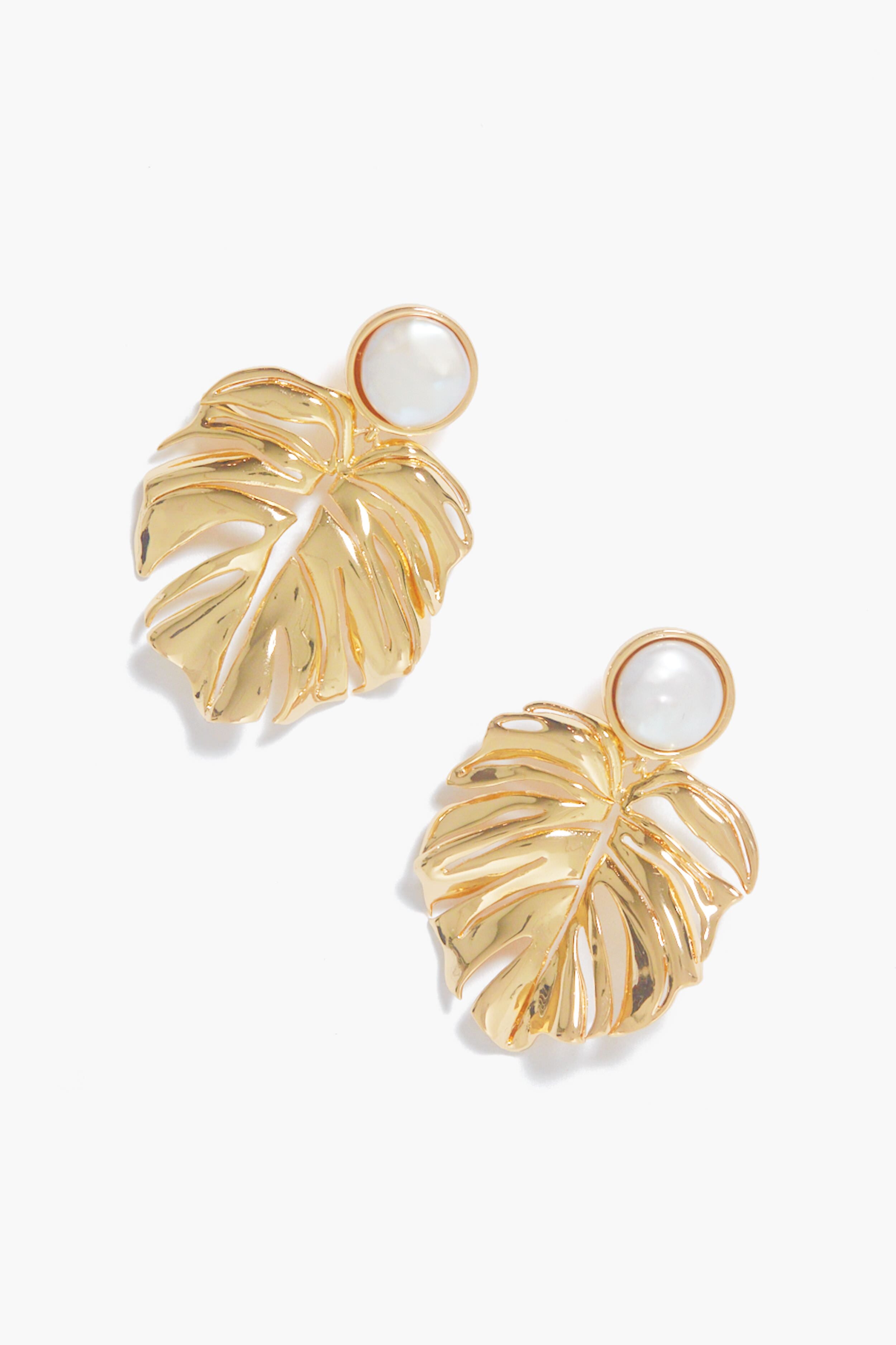 Mignonne Gavigan’s gold-plated Lux Palm Pearl Earrings feature elegant monstera leaf shapes with chic round white pearl accents at the top.