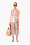 A woman in sunglasses, a boho-chic sleeveless patterned Tnuck Beach midi dress, and sandals holds a woven tote bag.
